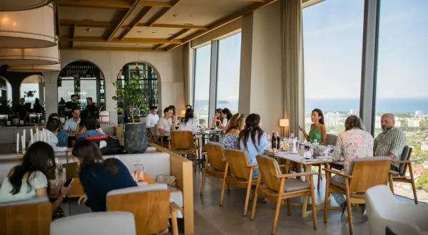 Goście delektują się posiłkiem w restauracji Olivia Star, przeglądając menu i podziwiając widok.