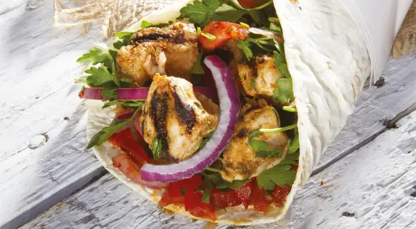 Kebab z grillowanym kurczakiem, warzywami i ziołami zawinięty w placek.