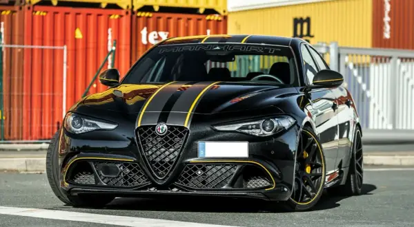 Czarna Alfa Romeo Quadrifoglio z żółtymi pasami i akcentami, gotowa do jazdy.