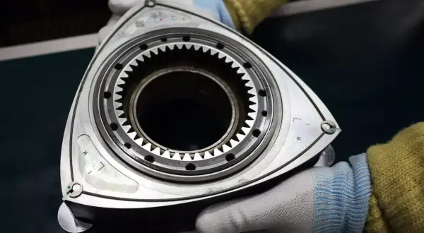 Rotor silnika Wankla, serce legendarnej Mazdy RX-3, w rękach mechanika.