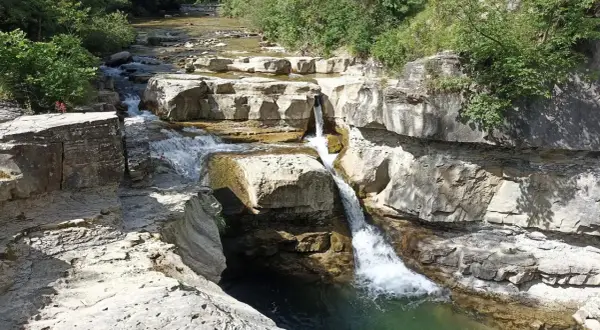 Cascate naturali scavate nella roccia vicino al monte Falterona. L'acqua cristallina scorre tra le rocce calcaree, creando un paesaggio suggestivo.