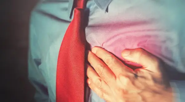 Mężczyzna w czerwonym krawacie trzyma się za serce. Beto czuje ból.