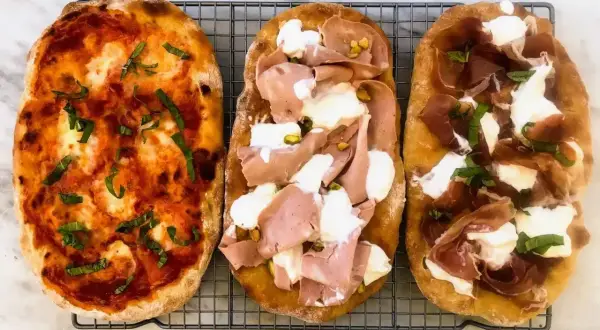 Trzy pyszne pinsy: jedna z sosem pomidorowym i bazylią, druga z mortadelą i pistacjami, trzecia z szynką parmeńską i mozzarellą. Tak wygląda pinsa co to!