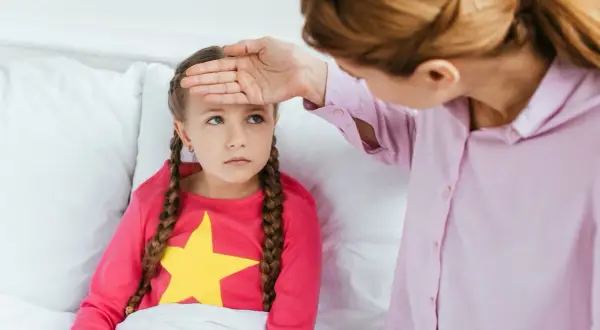 Mama sprawdza gorączkę córki, martwiąc się o objawy odwodnienia u dziecka.
