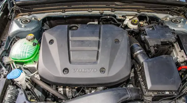 Silnik Volvo T3 z widocznym zielonym płynem w zbiorniczku i czarną osłoną z logo.