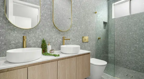 Modernos baños bonitos con lavabos sobre encimera, grifería dorada y azulejos de terrazo gris.