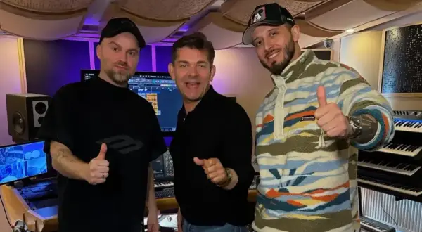 Mariusz Kalaga, jedna z gwiazd, w studiu nagraniowym z przyjaciółmi. Wszyscy pokazują kciuki w górę, gotowi do tworzenia muzyki.