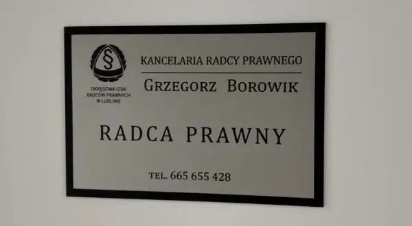 Tabliczka z napisem "Kancelaria Radcy Prawnego Grzegorz Borowik", z logo i numerem telefonu.