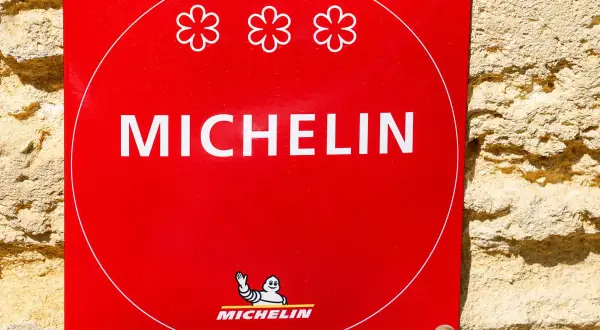 Targa rossa Michelin con tre fiori, simbolo di un ristorante 3 stelle Michelin.