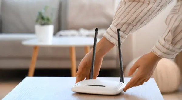Ręce dotykają routera Wi-Fi. Chcesz wiedzieć, jak sprawdzić hasło do Wi-Fi?