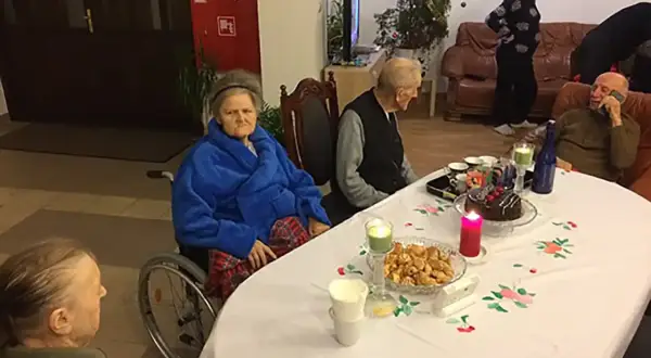 Wspólne świętowanie w domu seniora Zacisze. Przy stole tort, ciastka i świece.