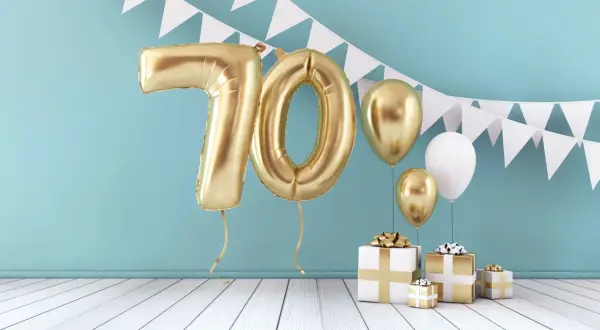 Złote balony z cyfrą 70 i prezenty tworzą piękną scenografię na życzenia na 70 urodziny.