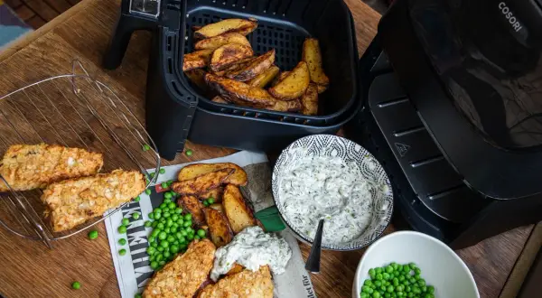 Krispiga fiskpinnar och klyftpotatis från airfryern, serverade med ärtor och en krämig dipp. Ett perfekt airfryer recept!