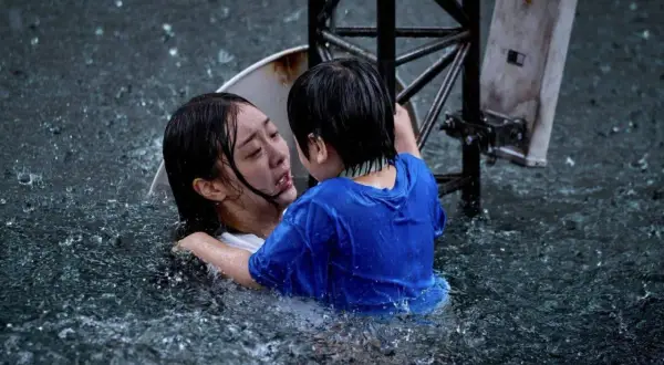 Dramatyczna scena z najlepszych filmów koreańskich: dziecko obejmuje tonącą kobietę w ulewnym deszczu.
