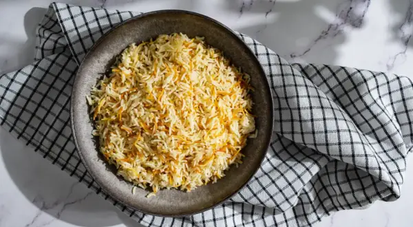 Un plat de riz libanais, parsemé de vermicelles dorés, servi sur une serviette à carreaux.