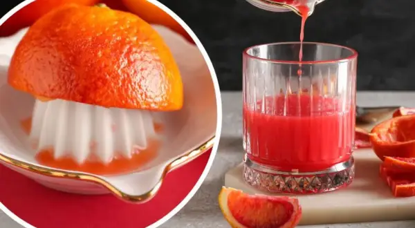 Świeżo wyciskany sok z grejpfruta w szklance, obok połówka owocu na wyciskarce i kawałki grejpfruta.