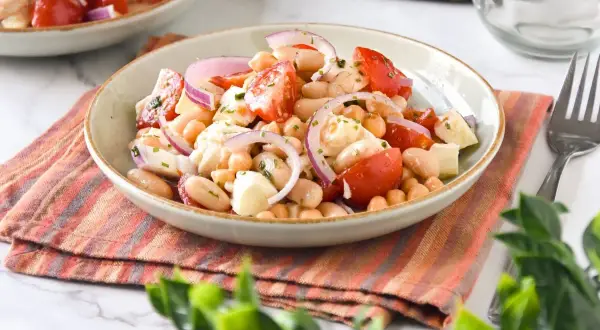 Ensalada de legumbres fresca con garbanzos, judías blancas, tomate y cebolla morada.