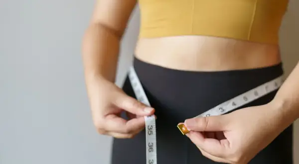 Kobieta mierzy talię centymetrem. Czy to oznaka szybkiego metabolizmu?