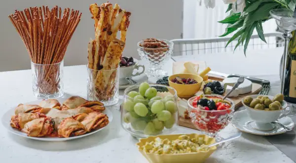 Leckere Fingerfood Ideen: Gebäck, Käse, Trauben, Oliven und mehr auf einer festlich gedeckten Tafel.