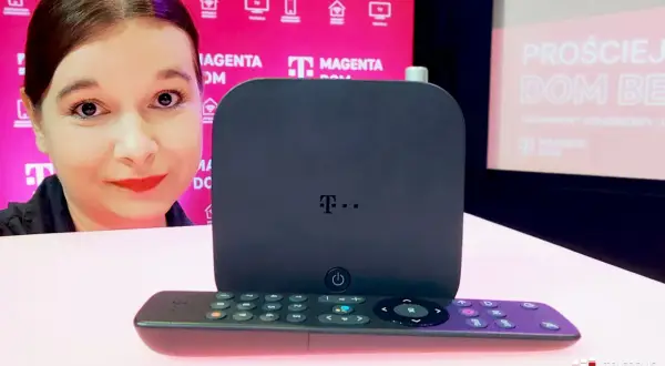 Kobieta prezentuje nowoczesne urządzenie do telewizji T-Mobile. Obok stoi pilot.