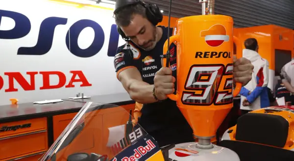 Mecánico repostando moto de competición con gasolina 100 octanos Repsol. El número 93 destaca en el depósito.