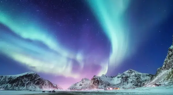 Spektakuläres Nordlicht tanzt über schneebedeckte Berge. Ein magisches Polarlicht-Erlebnis in der arktischen Nacht.