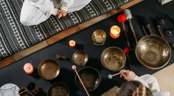 Operatore olistico stipendio: ciotole tibetane, candele e bacchette per un massaggio sonoro rilassante.