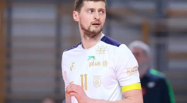 Piotr Nowakowski, siatkarz w białej koszulce z numerem 11, z uwagą obserwuje grę.
