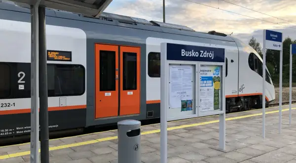 Pociąg do Buska Zdroju na peronie. Tablica informacyjna z nazwą stacji i rozkładem jazdy. Jak dojechać pociągiem do Buska Zdroju? Tu znajdziesz odpowiedź.