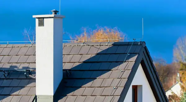 Na dachu domu widoczna jest instalacja odgromowa, chroniąca przed uderzeniami pioruna.