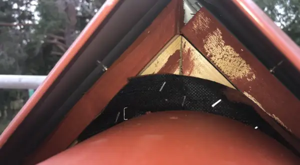 Detaljbild av taknock med vindskiveplåt och trädetaljer.