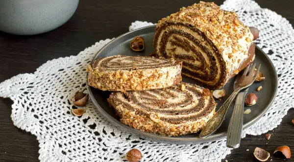 Un delizioso rotolo alla Nutella, ricoperto di granella di nocciole, pronto per essere gustato.