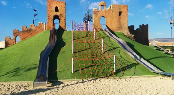 Un castillo de juguete con toboganes y red de escalada en un parque de las familias.