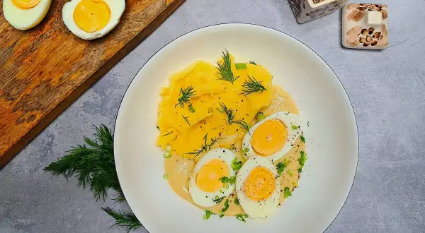 Jajka w sosie musztardowym z puree ziemniaczanym, udekorowane koperkiem i szczypiorkiem. Pyszne danie na obiad.