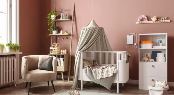 Une chambre de bébé chaleureuse avec un lit à baldaquin, une chaise confortable et des étagères pleines de jouets. Parfait pour une diy déco chambre bébé.