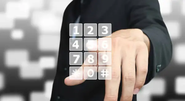 Dłoń wybiera wirtualny numer telefonu na ekranie.