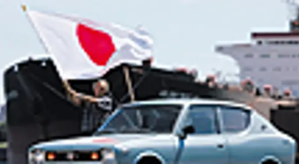 Jasnoniebieski Datsun 100A z flagą Japonii na tle statku.