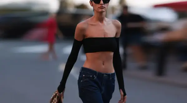 Frau im Y2K-Stil mit bauchfreiem Top und Jeans, die die Bedeutung von Mode für die Selbstentfaltung verkörpert.