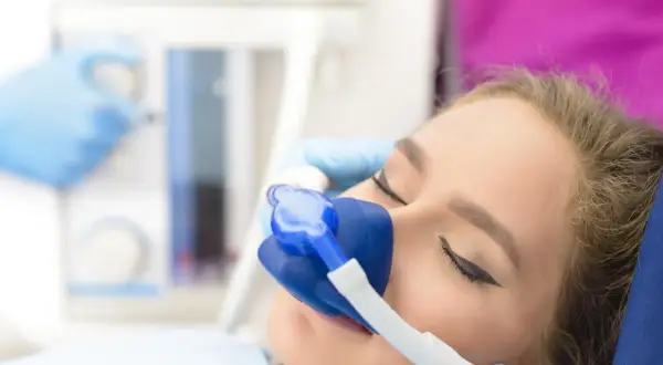 Pacjentka z maską do sedacji wziewnej, prawdopodobnie z użyciem midanium, podczas zabiegu stomatologicznego.