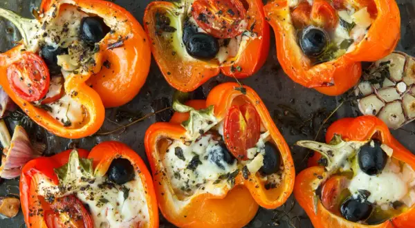 Poivrons orange farcis de fromage, olives et tomates, assaisonnés d'herbes. Un délice de poivrons marinés prêt à être dégusté.