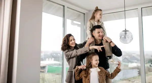 Famiglia felice in una casa luminosa, con la madre che indica il futuro. Nonostante si possa vendere casa senza lasciare a mio figlio nulla, l'amore è il vero patrimonio.