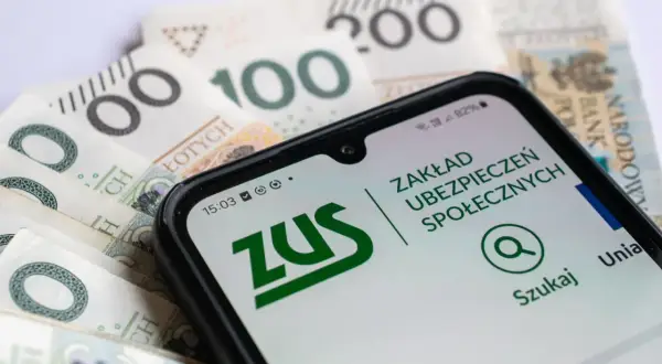 Telefon z aplikacją ZUS na tle polskich banknotów. Sprawdzanie informacji o 13 emeryturze 2026 w tabeli.