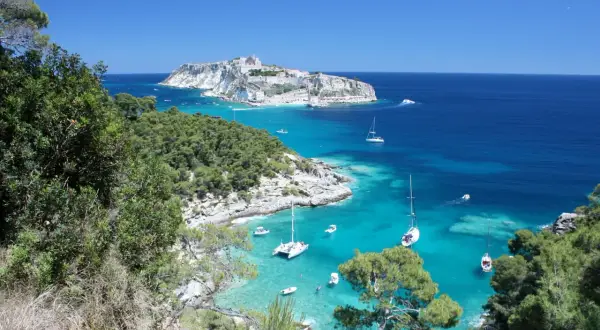 Vista mozzafiato di San Nicola di Tremiti, con il castello in lontananza e barche a vela nelle acque cristalline. Perfetto per scoprire le cose da fare a San Nicola di Tremiti.