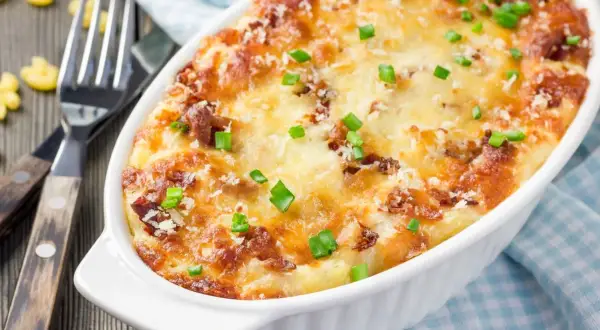 Zapiekane mac and cheese z chrupiącym serem i zieloną cebulką, gotowe do podania.