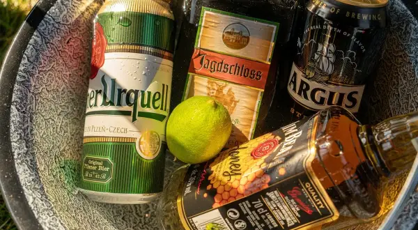 Puszki piwa i butelka whiskey w misce. Zastanawiasz się, ile chmielu do piwa?