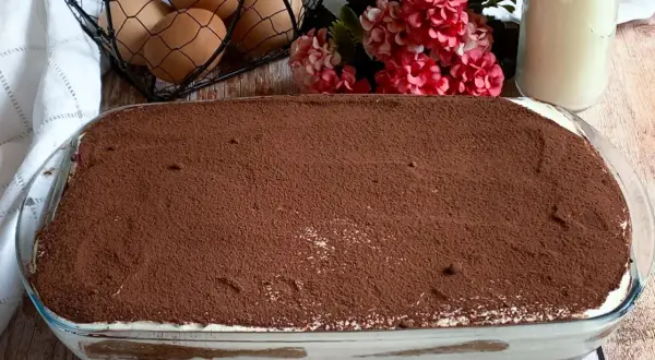 Tiramisù pronto per essere gustato! La ricetta tiramisù con 500 g mascarpone è un classico. Uova, fiori e latte completano la scena.