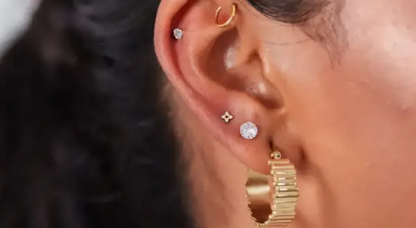 Ucho ozdobione kilkoma kolczykami, w tym subtelnym anti tragus piercing z małym kamieniem.
