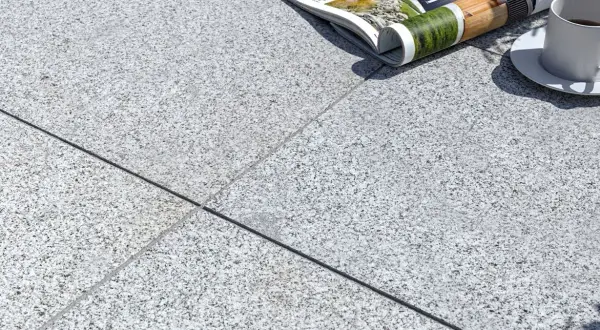 Una tazza di caffè e una rivista appoggiate su una composizione granito. La luce del sole crea ombre suggestive.
