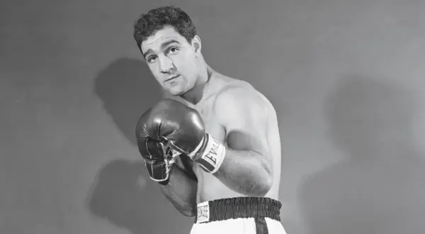 Boxer Rocky Marciano poses with his powerful Rocky Marciano hands in boxing gloves, ready for action.