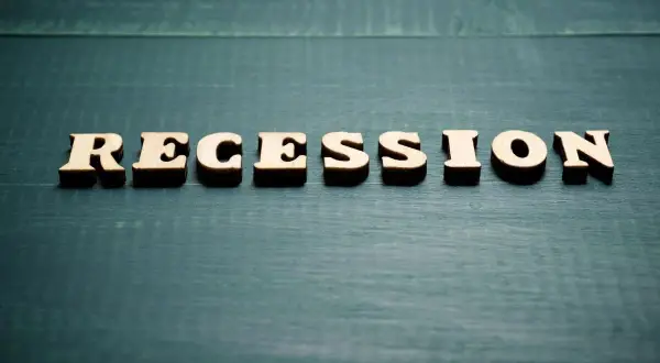Drewniane litery układają słowo "RECESSION". To pojęcie ekonomiczne, które opisuje spowolnienie gospodarcze.